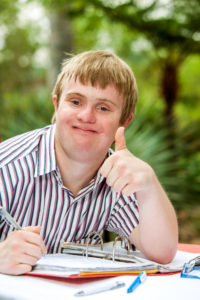 35502540 - close up portrait of handicapped student doing thumbs up at desk outdoors.